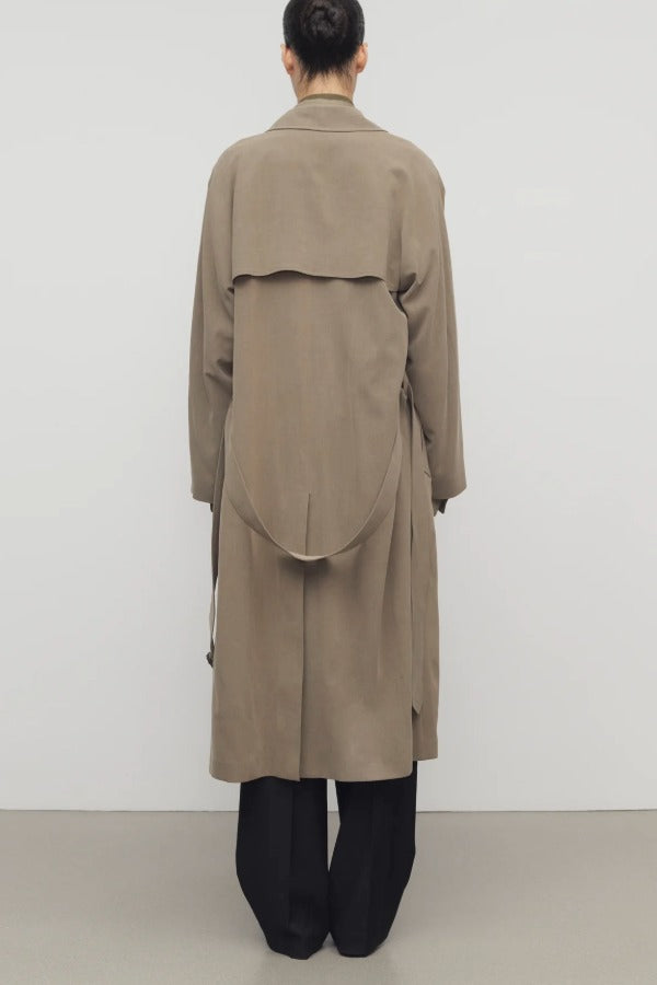 Back view of beige grey rhydian coat on model wearing black pants, against a white background.