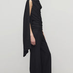 Side view of black roger pant on model wearing black top and heels, against a white background.