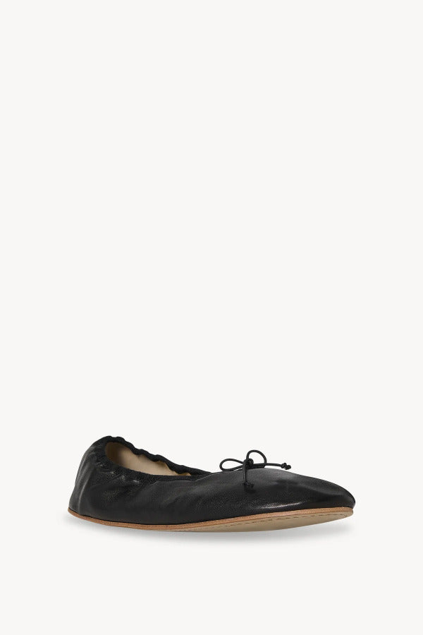 Front slanted view of black round ballet flats on white background, with no model shown.