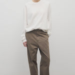 Front view of taupe sharka pant on model wearing white t-shirt and slides, against a white background.