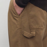 Side closeup view of dark sand sharka pant on model wearing black top, against a white background.