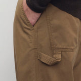 Side closeup view of dark sand sharka pant on model wearing black top, against a white background.