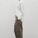 Side view of taupe sharka pant on model wearing white t-shirt and slides, against a white background.