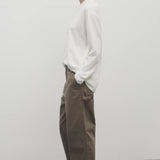 Side view of taupe sharka pant on model wearing white t-shirt and slides, against a white background.