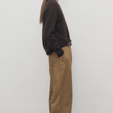 Side view of dark sand sharka pant on model wearing black top, against a white background.