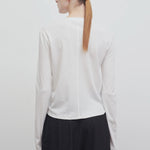 Back view of white sherman t-shirt on model wearing black trousers, against a white background.