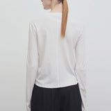 Back view of white sherman t-shirt on model wearing black trousers, against a white background.