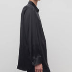 Side view of black sisilia shirt on model wearing black pants, against a white background.