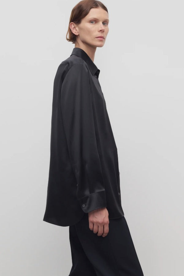 Side view of black sisilia shirt on model wearing black pants, against a white background.