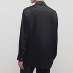 Back view of black sisilia shirt on model wearing black pants, against a white background.