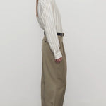 Side view of military beige sorina pant on model wearing a striped shirt and flats, against a white background.