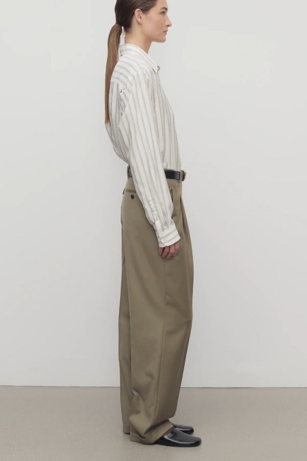 Side view of military beige sorina pant on model wearing a striped shirt and flats, against a white background.