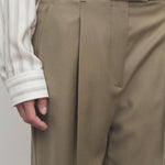 Front closeup of military beige sorina pants on model wearing striped shirt and black belt, against a white background.