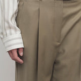 Front closeup of military beige sorina pants on model wearing striped shirt and black belt, against a white background.