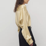 Side view of sand takara shirt on model wearing black pants, against a white background.