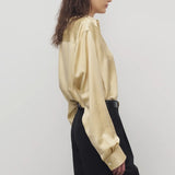 Side view of sand takara shirt on model wearing black pants, against a white background.
