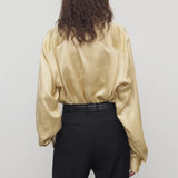 Back view of sand takara shirt on model wearing black pants and belt, against a white background.