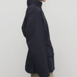 Side view of navy tanera jacket on model wearing khaki pants, against a white background.
