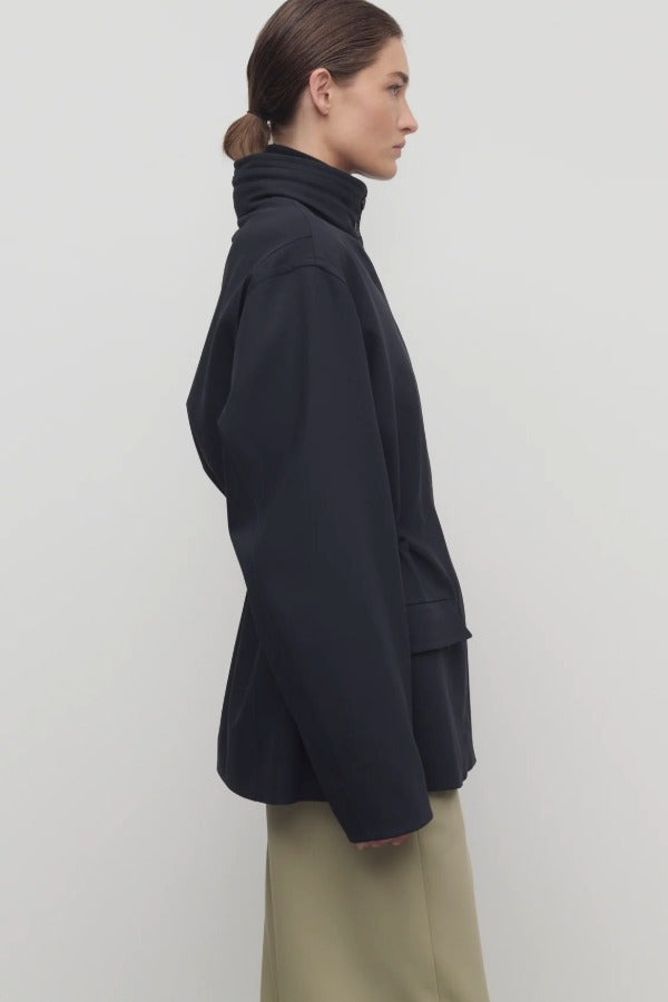 Side view of navy tanera jacket on model wearing khaki pants, against a white background.