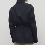 Back view of navy tanera jacket on model wearing khaki pants, against a white background.