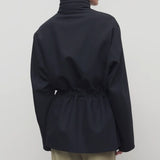 Back view of navy tanera jacket on model wearing khaki pants, against a white background.