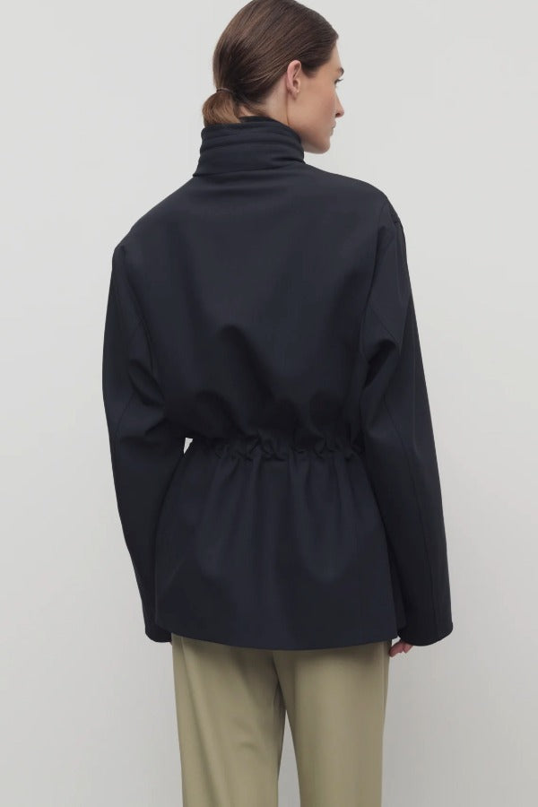 Back view of navy tanera jacket on model wearing khaki pants, against a white background.