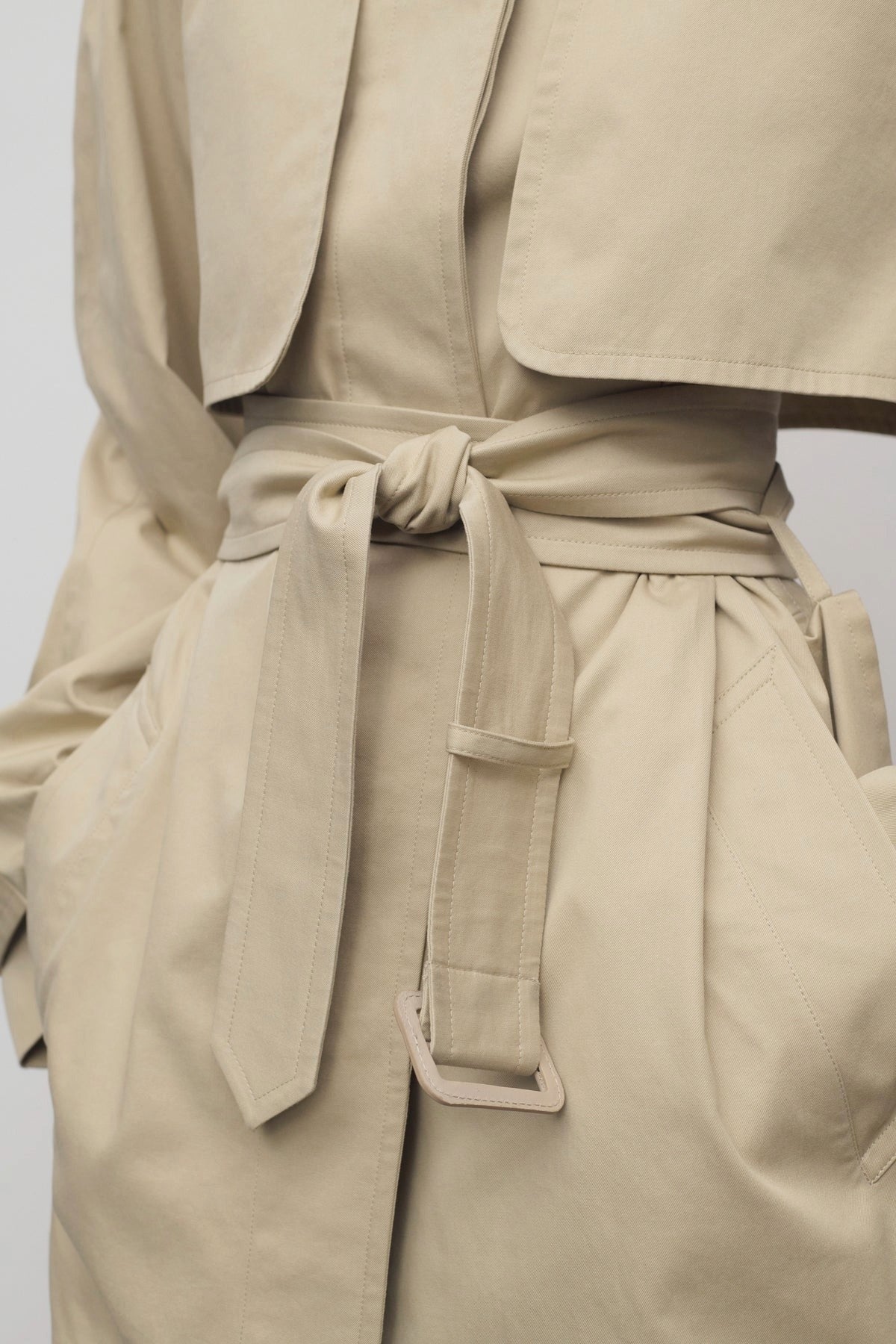 Front closeup of belt in sandstone tavoris jacket on model against a white background.