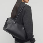 Front view of black terrasse bag on model wearing grey pants and charcoal sweater, against a white background.