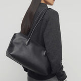 Front view of black terrasse bag on model wearing grey pants and charcoal sweater, against a white background.