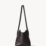 Side view of dark brown terrasse bag on white background, with no model shown.