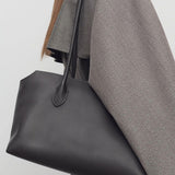 Front view of dark brown terrasse bag on model wearing grey coat, against a white background.