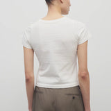 Back view of white tori top on model wearing khaki trousers against a white background.