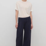 Front view of dark navy ukira pant on model wearing white t-shirt, against a white background.