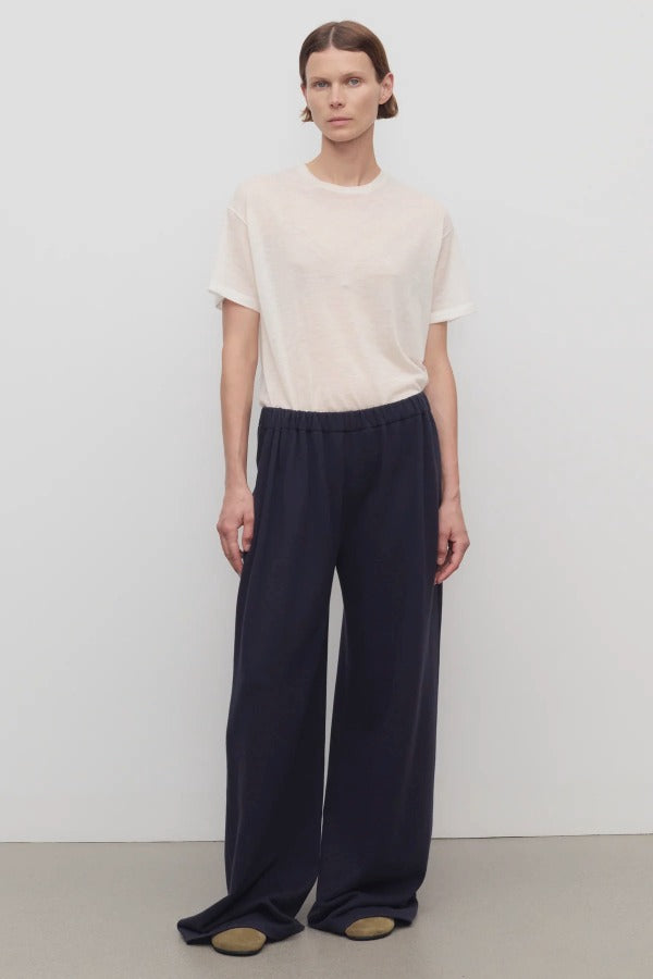 Front view of dark navy ukira pant on model wearing white t-shirt, against a white background.