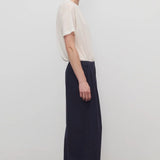 Side view of dark navy ukira pant on model wearing white t-shirt, against a white background.