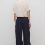 Back view of dark navy ukira pant on model wearing white t-shirt, against a white background.