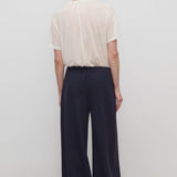Back view of dark navy ukira pant on model wearing white t-shirt, against a white background.