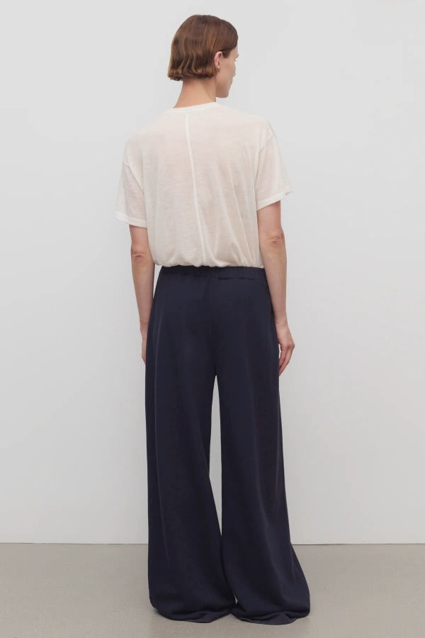 Back view of dark navy ukira pant on model wearing white t-shirt, against a white background.