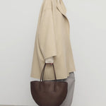 Side view of light pebble verlain coat on model wearing grey pants, against a white background.