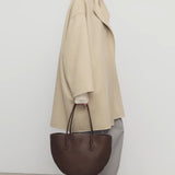 Side view of light pebble verlain coat on model wearing grey pants, against a white background.