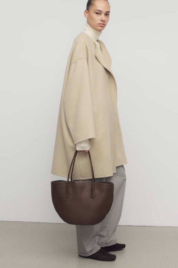 Side view of light pebble verlain coat on model wearing grey pants, against a white background.