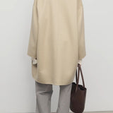Back view of light pebble verlain coat on model wearing grey pants, against a white background.
