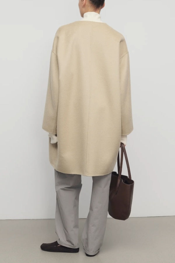 Back view of light pebble verlain coat on model wearing grey pants, against a white background.