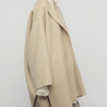 Side view of light pebble verlain coat on model wearing grey pants, against a white background.