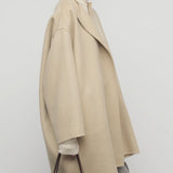 Side view of light pebble verlain coat on model wearing grey pants, against a white background.