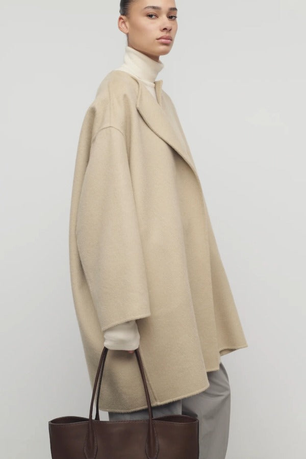 Side view of light pebble verlain coat on model wearing grey pants, against a white background.