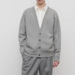 Front view of grey melange vonn cardigan on model wearing grey trousers and a white shirt, against a white background.