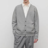 Front view of grey melange vonn cardigan on model wearing grey trousers and a white shirt, against a white background.