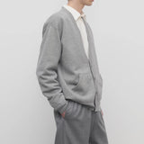 Side view of grey melange vonn cardigan on model wearing grey trousers and a white shirt, against a white background.