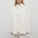 Front view of white button down elodianna jacket on model wearing white shirt and white trousers on white background.